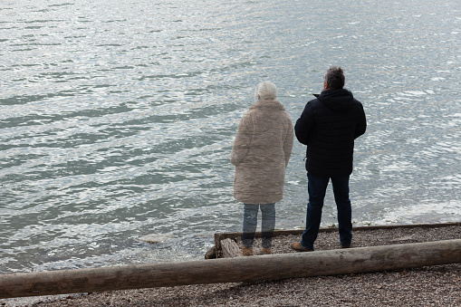Lonely man standing by the lake with ghost of a woman standing by his side, staring in the distance