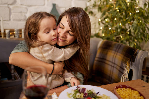 istock Loving single mother and daughter embracing at dining table. 1390261990