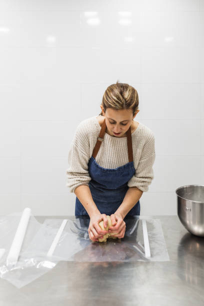 istock Female baker kneading dough on table in bakery 1390263802