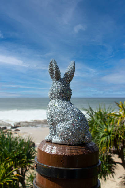 istock Silver sparkly glitter Easter Bunny at the beach.  Sitting on a brown post looking out to the ocean. Ocean & sky in the background with Pandanus trees down below. Gold Coast Queensland Australia 1390265707