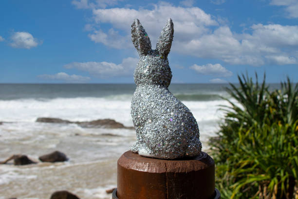 istock Silver sparkly glitter Easter Bunny at the beach.  Sitting on a brown post looking out to the ocean. Ocean & sky in the background with Pandanus trees down below. Gold Coast Queensland Australia 1390265735