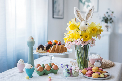 Pastel color Easter table decoration with a sweet Easter bunny and spring flower bouquet.