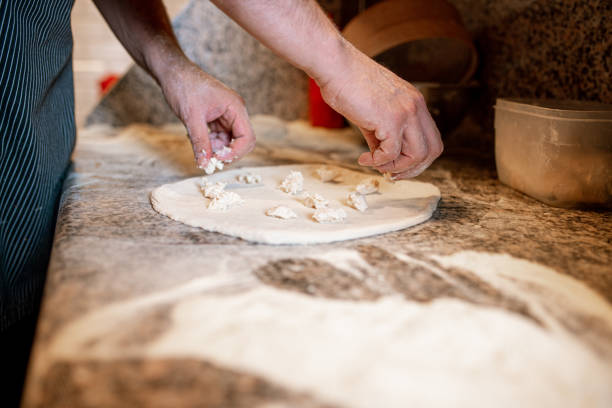 istock Putting mozzarella pieces on pizza dough lying flat on kitchen counter 1390274656