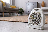 Modern electric fan heater on floor at home. Space for text