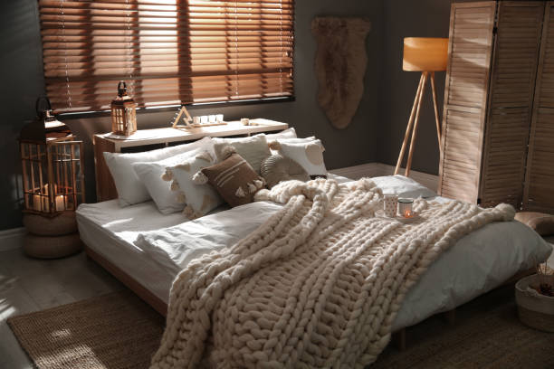 istock Cozy bedroom interior with knitted blanket and cushions 1390275546