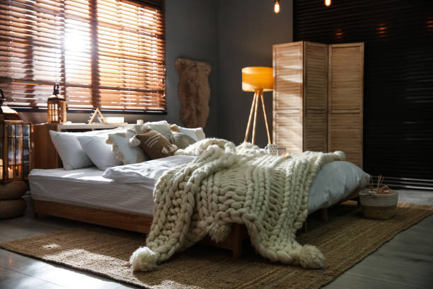 Cozy bedroom interior with knitted blanket and cushions