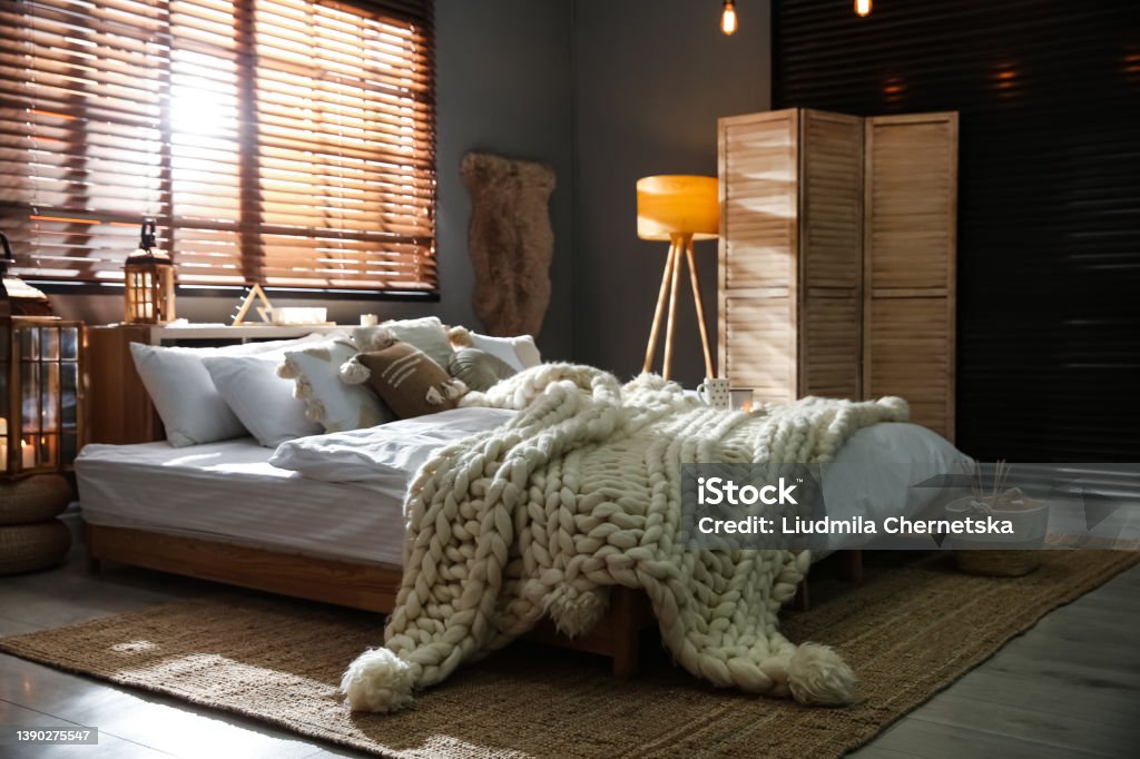 Cozy bedroom interior with knitted blanket and cushions Bedroom Stock Photo