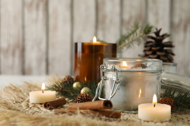 istock Burning scented conifer candles and Christmas decor on table. Space for text 1390275560