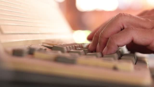Close-up view of fingers swiftly pressing letters on an old typewriter keypad.
