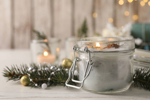 istock Burning scented conifer candle and Christmas decor on white wooden table. Space for text 1390277020