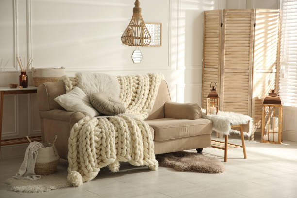 Cozy living room interior with beige sofa, knitted blanket and cushions Cozy living room interior with beige sofa, knitted blanket and cushions hygge photos stock pictures, royalty-free photos & images