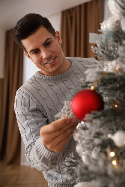istock Handsome man decorating Christmas tree at home 1390280218