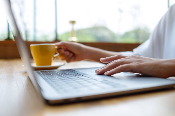 istock Closeup image of a woman working and touching on laptop computer touchpad while drinking coffee 1390282022
