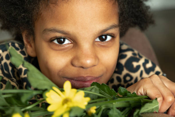 Portrait of a cute African-American girl with a bouquet of yellow flowers at home.Diverse people