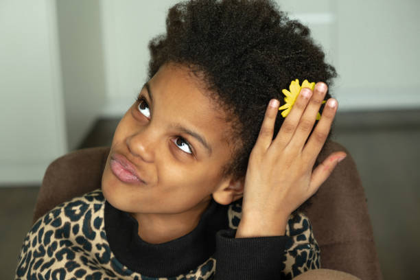 Portrait of a cute African-American girl posing with a yellow flower in her hair.Diverse people