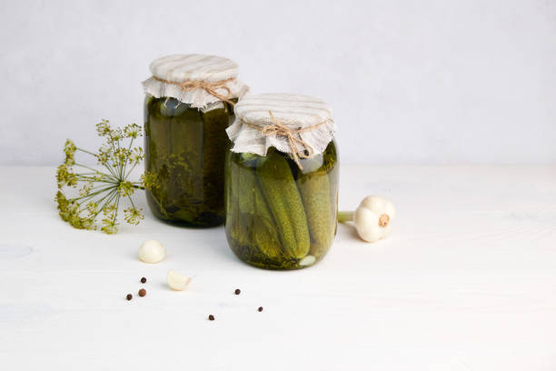 istock Pickled cucumbers in jars on a white wooden background. 1390288060