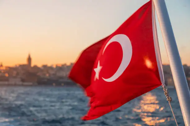 Waving Turkish flag on a ferry boat against Bosporus or Strait of Istanbul at sunset