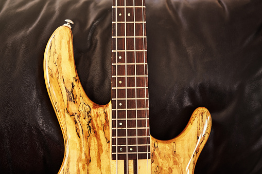 Electric bass guitar resting on a leather couch.