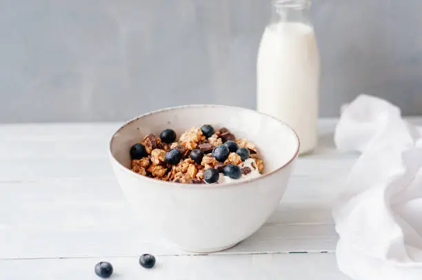 Granola with blueberries and chocolate in a bowl standing on a table