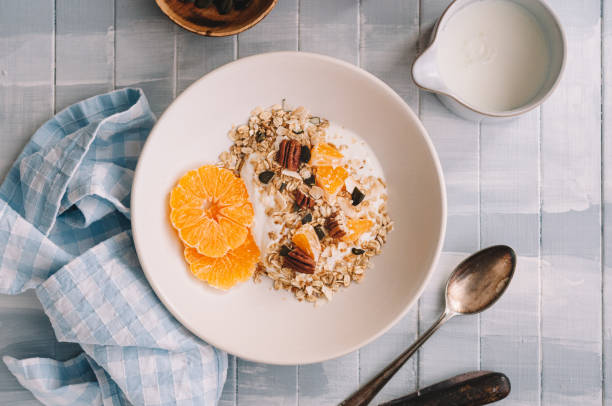 Oatmeal with yogurt and tangerine on a white plate standing on a table