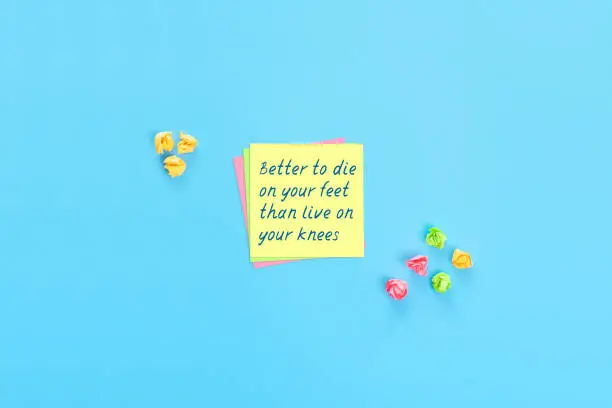 Sticky notes with handwritten text Better to die on your feet than live on your knees. Motivational statement.
