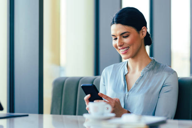 istock Cheerful Businesswoman Using Mobile Phone in the Restaurant 1390298132