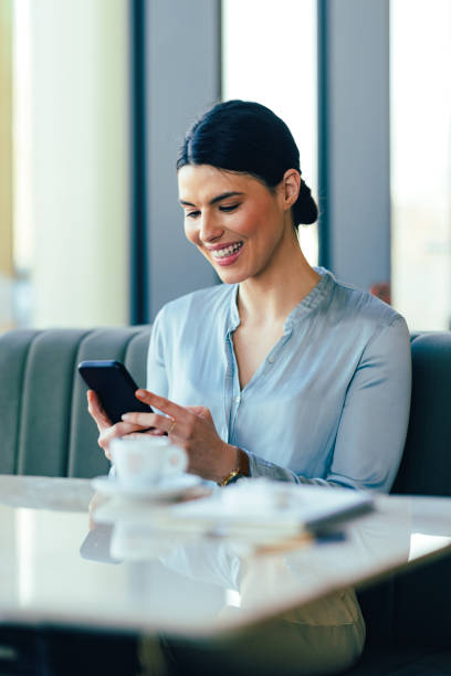 istock Smiling Businesswoman Using Mobile Phone in the Restaurant 1390298135