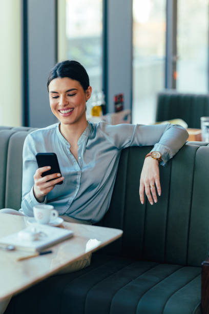 istock Smiling Businesswoman Using Mobile Phone in the Restaurant 1390298146