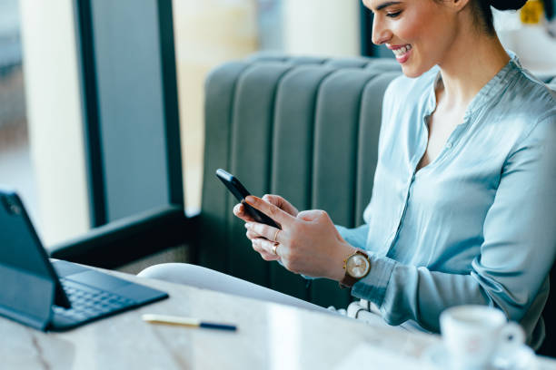 istock Smiling Businesswoman Using Mobile Phone in the Restaurant 1390298203
