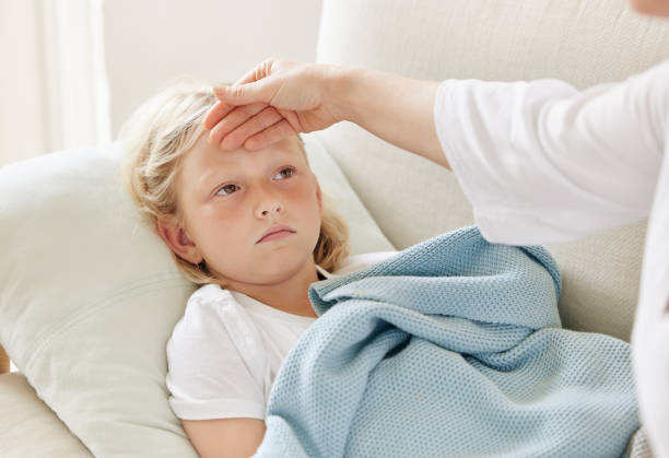istock Shot of a mother checking her daughters temperature on the sofa at home 1390298917