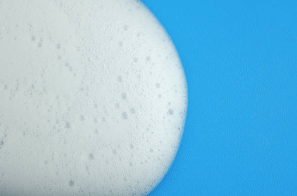 Macro photo of white shampoo foam on blue background