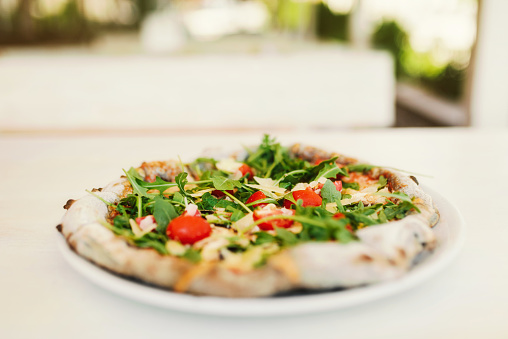 Vegetarian pizza with tomatoes, rucola and parmesan.