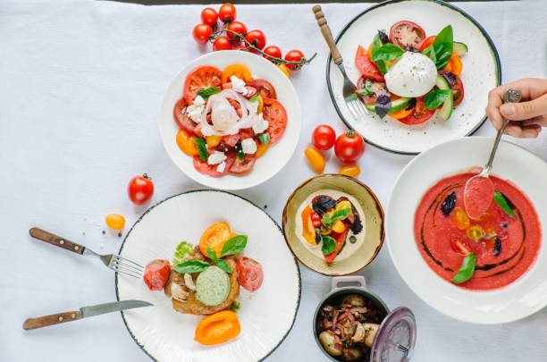 variety of dishes on the table. tomato menu in the restaurant, tomato soup, mix of tomatoes with buffalo mozzarella and pesto, pork fillet with baked tomatoes, pasta with tomato sauce, tomato salad. top view - basil tomato soup food and drink imagens e fotografias de stock