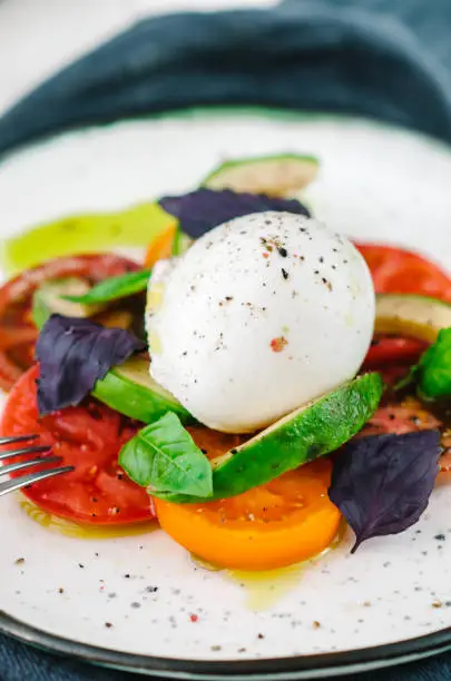 Buffalo burrata cheese served with fresh raw tomatoes and basil leaves