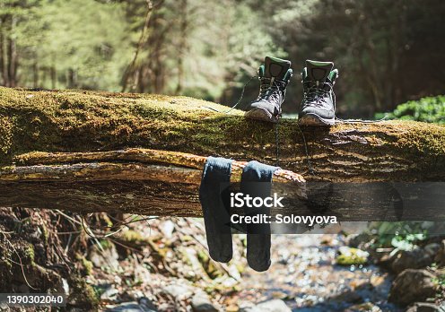 istock Pair of high trekking high-top boot drying up with wet socks on the felled over forest creek tree under the warm autumn sun. Active people in Nature concept image. 1390302040