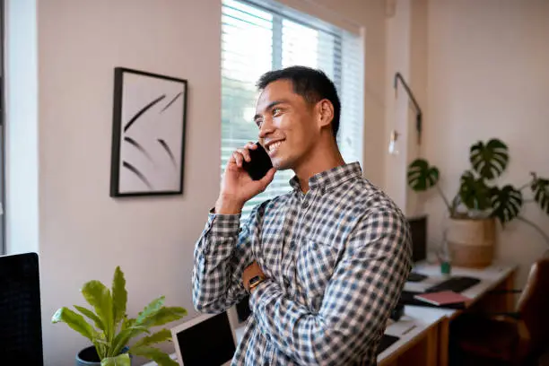 A young businessman smiles on a phonecall in an empty office. High quality photo