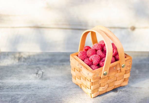 basket with raspberries on wooden background close up