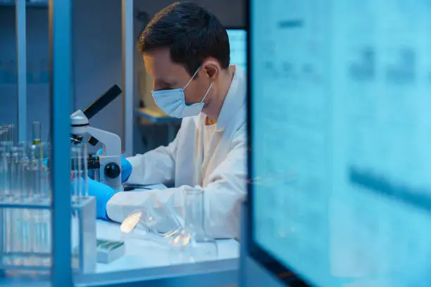 Photo of A molecular biologist working with a microscope in a modern scientific Laboratory