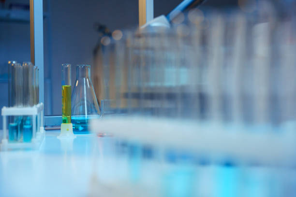 racks de tubo de ensaio com tubos de teste de vidro e frascos de laboratório com líquidos coloridos em uma mesa em um laboratório científico moderno - fundação de pesquisa - fotografias e filmes do acervo