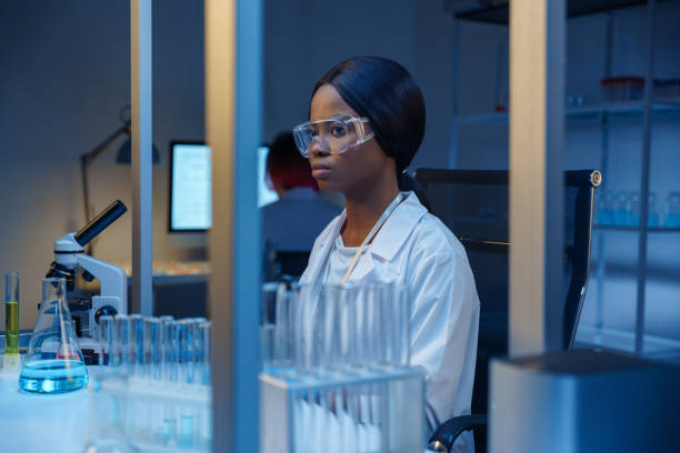 A young beautiful concentrated microbiologist in protective glasses in a modern laboratory