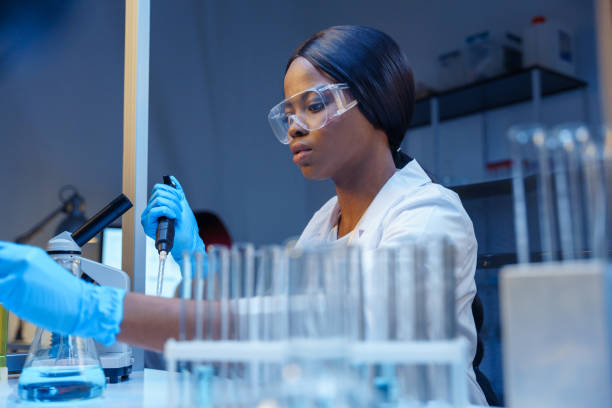 istock A young, beautiful, focused laboratory worker in protective glasses at her desk with laboratory flasks and glass test tubes in a test tube rack 1390303384