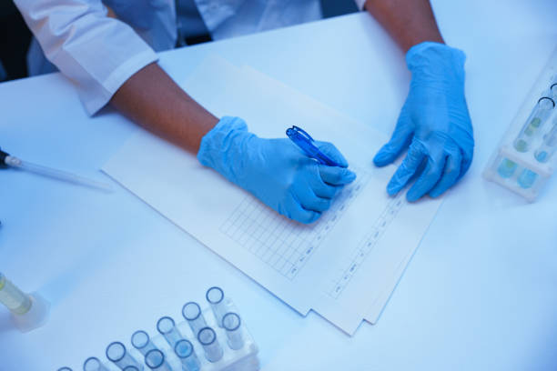 A scientist in protective medical gloves  writes test results we see it from the top view, only hands are in the frame