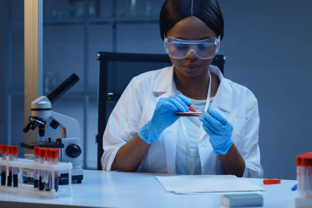 istock A young African-American lab worker subscribing test tubes with blood samples, sitting at her desk in a modern medical laboratory, conducting blood analysis 1390303522