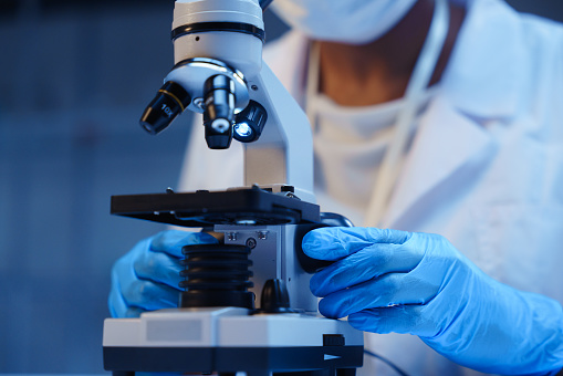 A doctor using a microscope in a modern lab, we see a microscope in close-up