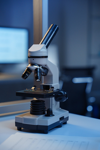 A microscope on a desk in a modern scientific laboratory on a blurred background
