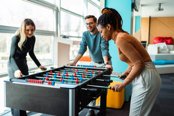 Coworkers playing foosball stock photo