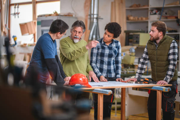istock Group of Diverse Carpenter Trainees Designing A Blueprint 1390310457