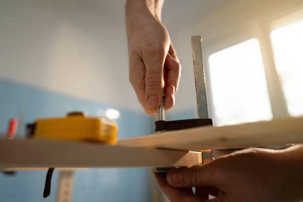 Unrecognizable male Caucasian carpenter adjusting clamp, while making furniture in the kitchen