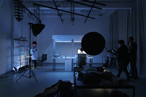 A backstage from filming a movie or a photoset with a scientific laboratory decorations and a filming crew at work around it