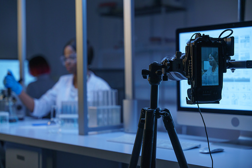 A professional camera shooting an actress in a role of a scientist in a laboratory. Backstage from filming a movie of a photo  set in a laboratory decorations